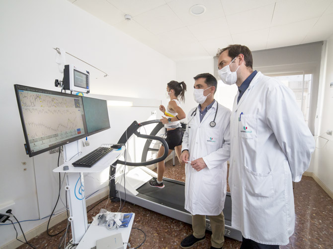 Dos médicos siguen el electrocardiograma mientras una deportista corre en la cinta durante una prueba de esfuerzo
